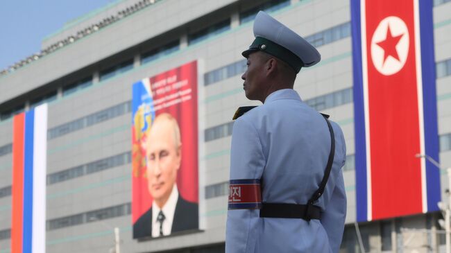 Постовой у здания, на котором вывешен портрет президента РФ Владимира Путина, в Пхеньяне